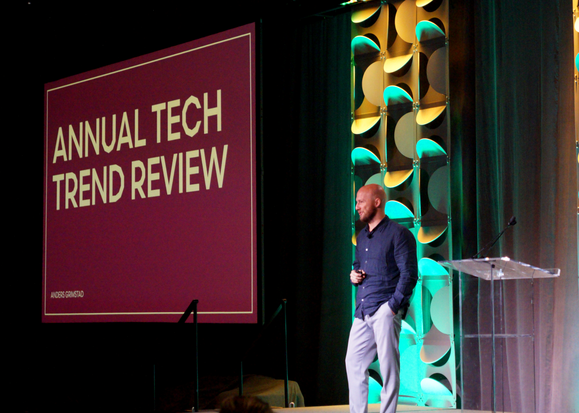 Anders Grimstad, a man from Norway, presents on stage. Behind him is a presentation screen that reads "Annual Tech Trend Review."